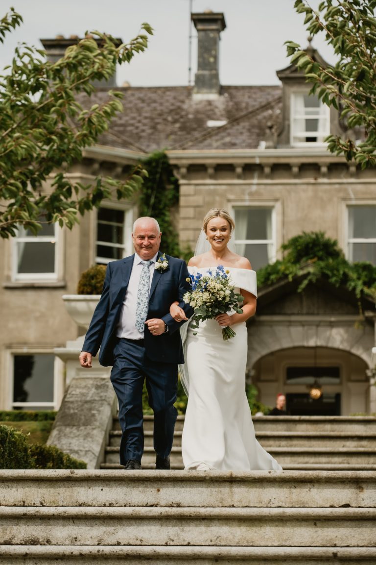 Magical and intimate moment as the bride and groom share their first kiss after the wedding ceremony at Tinakilly Country House in Ireland. The image captures pure emotion, love, and joy as family and friends witness this unforgettable moment. Bathed in natural light and framed by the elegant surroundings of the Irish country house, this fine art wedding photograph showcases the couple’s connection and the celebratory atmosphere of the day. Captured by WeddingWithMe, the photo exemplifies professional wedding photography and videography, perfect for luxury wedding websites, galleries, and social media.