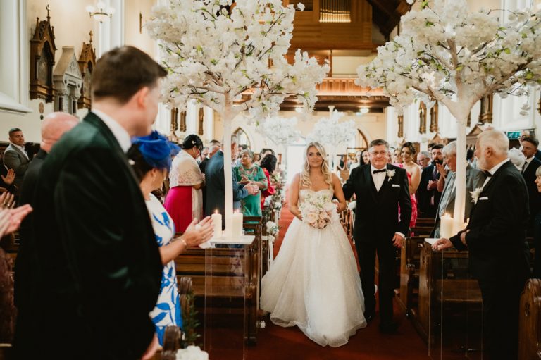 Dylan’s friends smiling during the wedding ceremony at Killashee Manor House in Ireland, capturing a joyful and relaxed moment inside the church. Their genuine happiness reflects the warm atmosphere of the day, adding a natural and candid touch to this Irish castle wedding story. Beautifully documented through authentic wedding photography by WeddingWithMe.