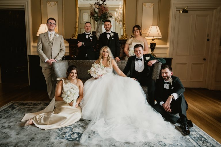 Elegant wedding portrait of the bride and groom standing on a grand staircase at Killashee Manor House in Ireland, not looking at each other. This composed and editorial-style image highlights sophistication, balance, and timeless style, with the architectural lines of the staircase enhancing the visual storytelling. Captured by WeddingWithMe, showcasing refined and artistic wedding photography.