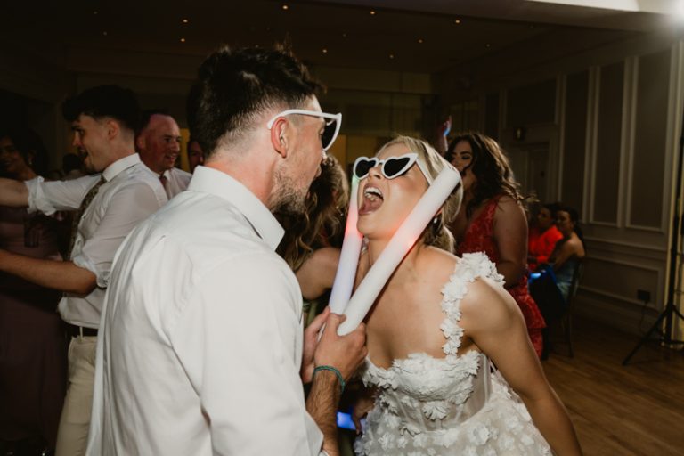 Couple dancing and celebrating at wedding party wearing glasses at Ballykealey House captured by WeddingWithMe in Ireland